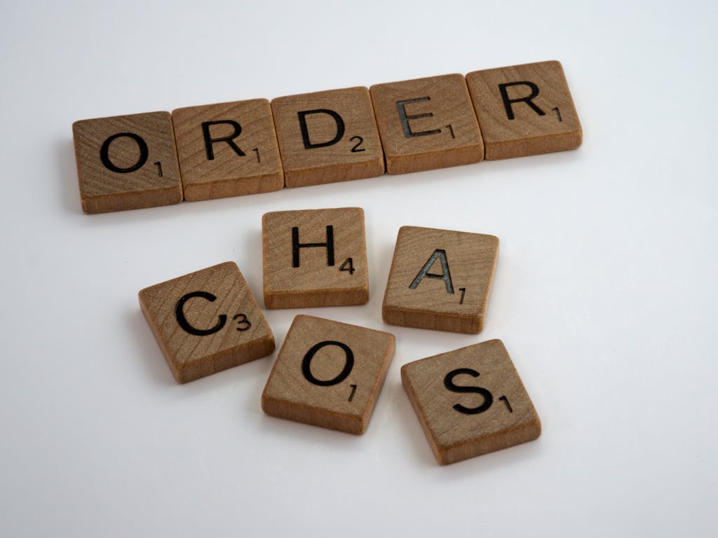 Scrabble tiles spelling 'ORDER' neatly lined up and 'CHAOS' jumbled on a white surface.