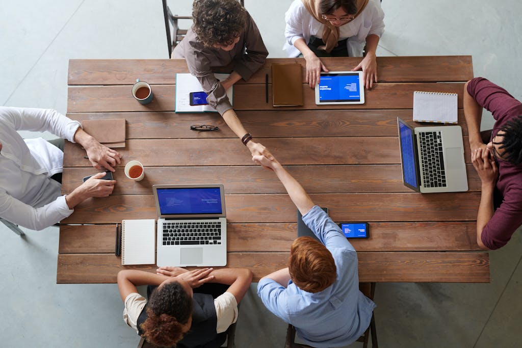 Overhead view of colleagues in a work meeting using laptops and tablets, emphasizing teamwork and technology to optimized bookkeeping systems